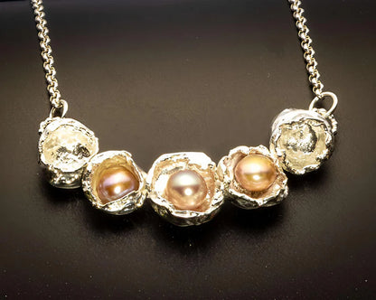 Necklace with pearls and textured metal elements on a dark background